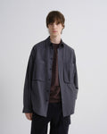 Man wearing a dark gray jacket over a brown shirt on a white background