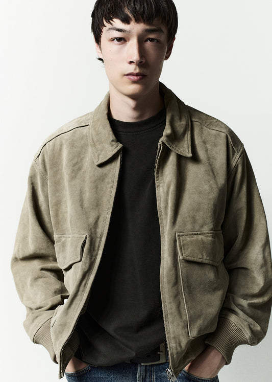 Man wearing a beige jacket over a black shirt on a white background