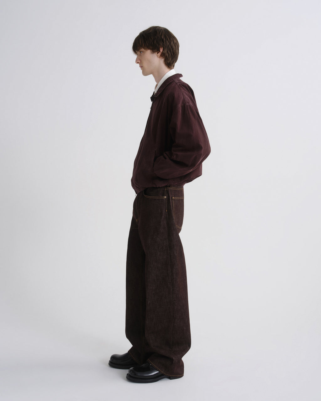 Person wearing a dark brown outfit on a white background