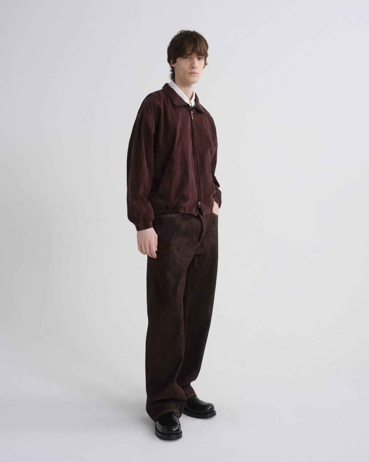 Person wearing a maroon jacket and pants on a white background