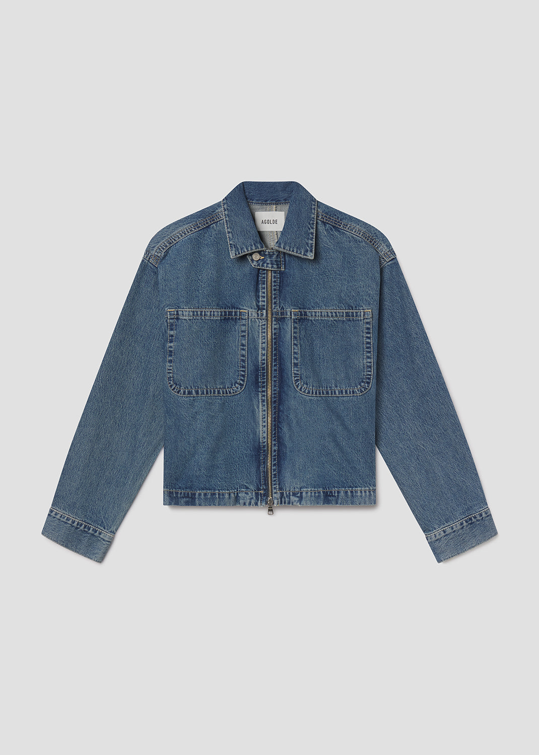 Flat lay of blue denim jacket on a light grey background