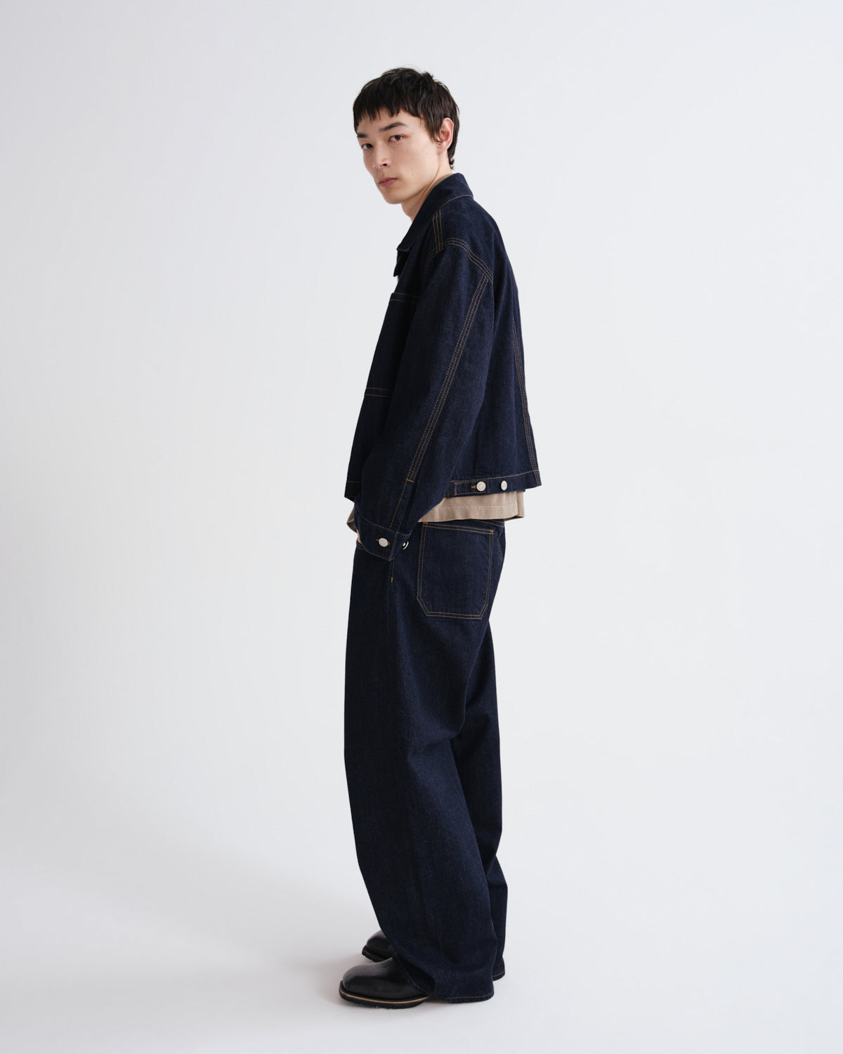 Person wearing a dark jacket and jeans on a white background