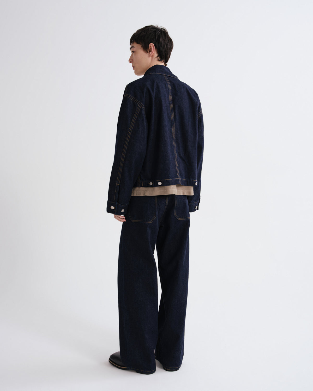 Person wearing a dark blue jacket and pants on a white background