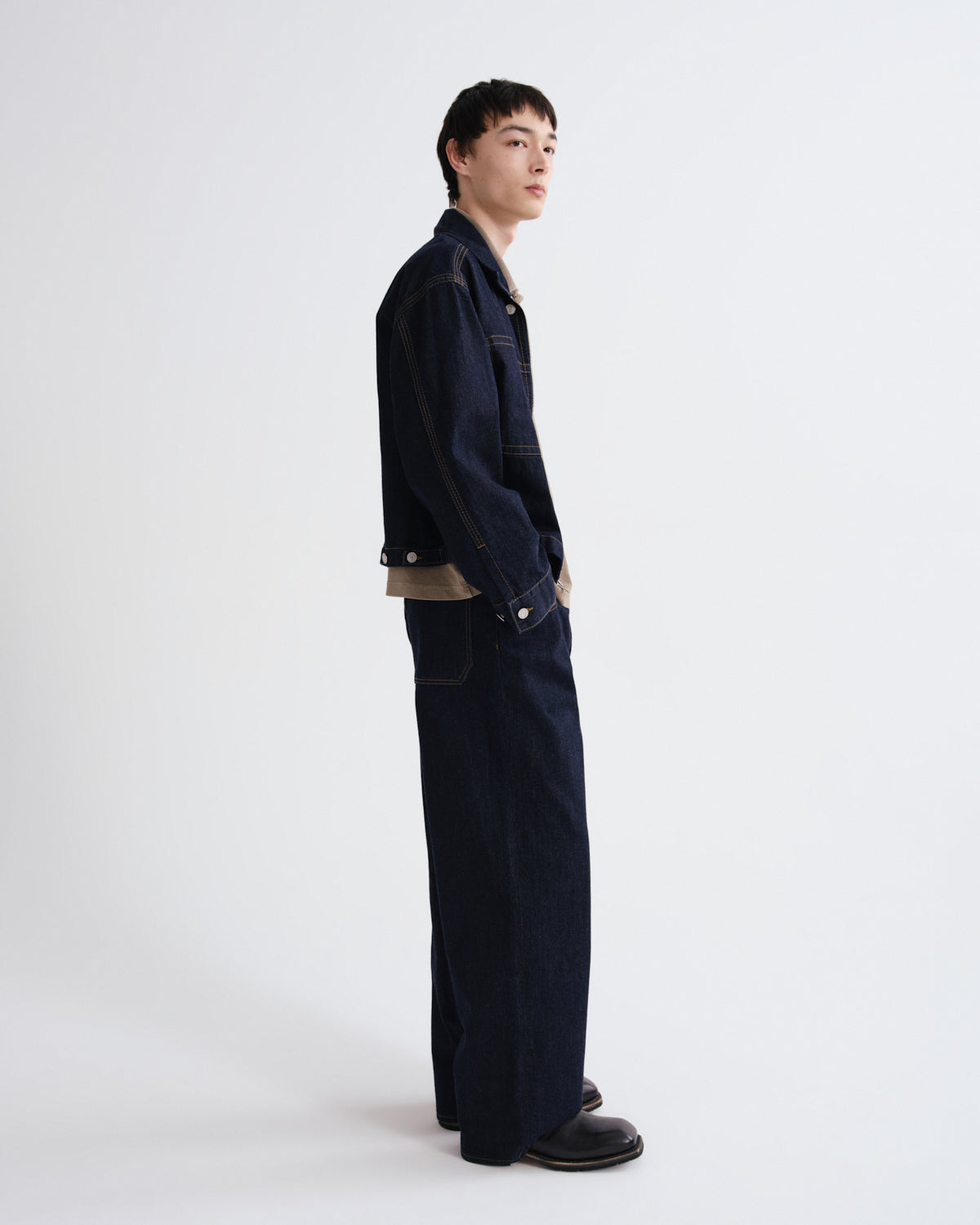 Person wearing a dark blue jacket and pants on a white background