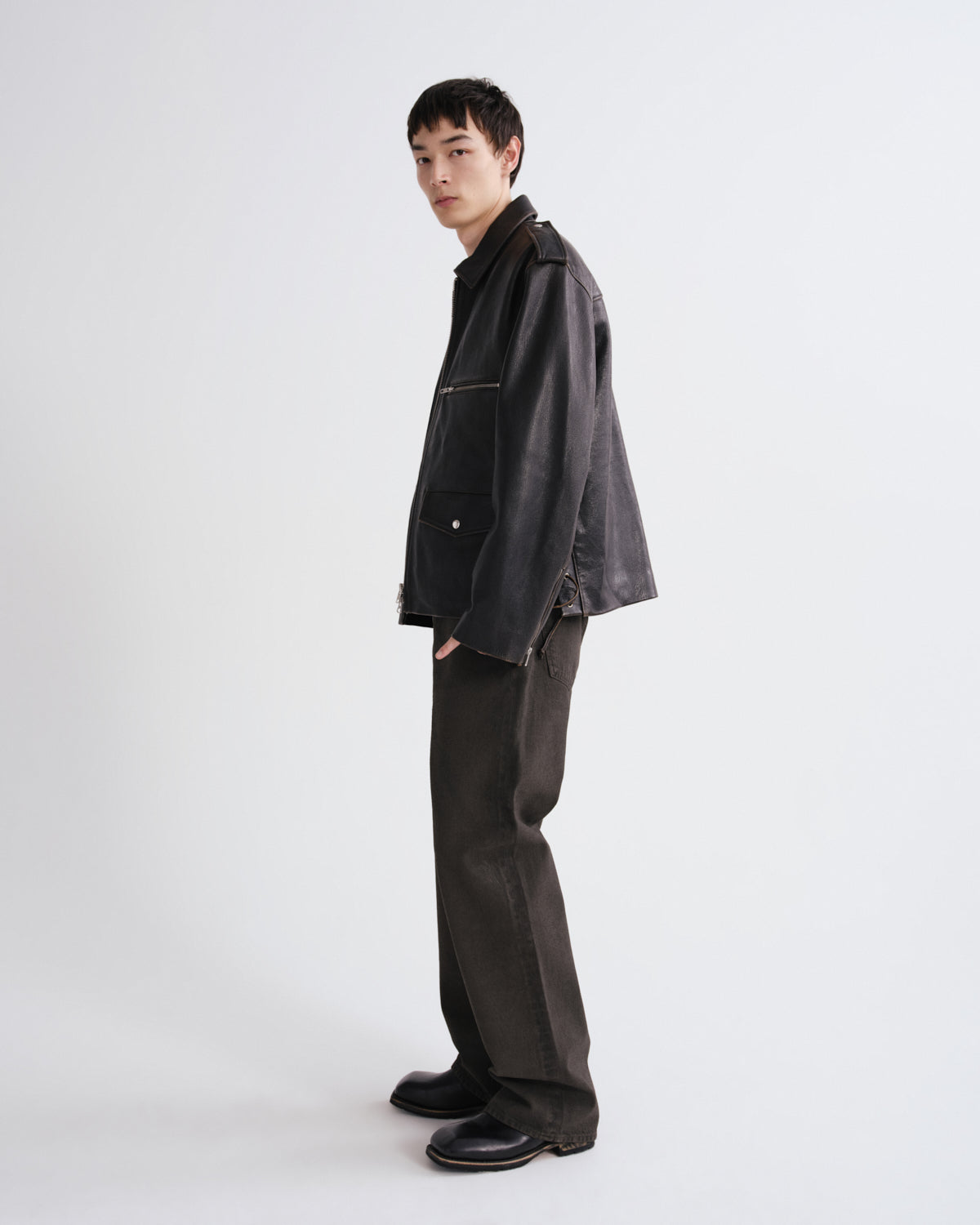 Person wearing a dark jacket and pants on a grey background