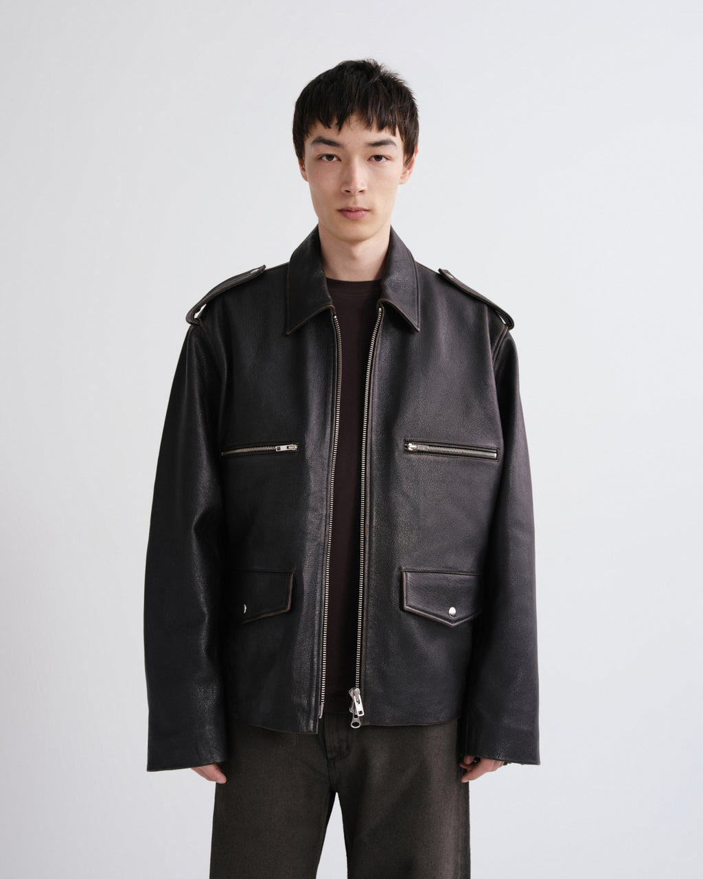 Man wearing a black leather jacket on a grey background