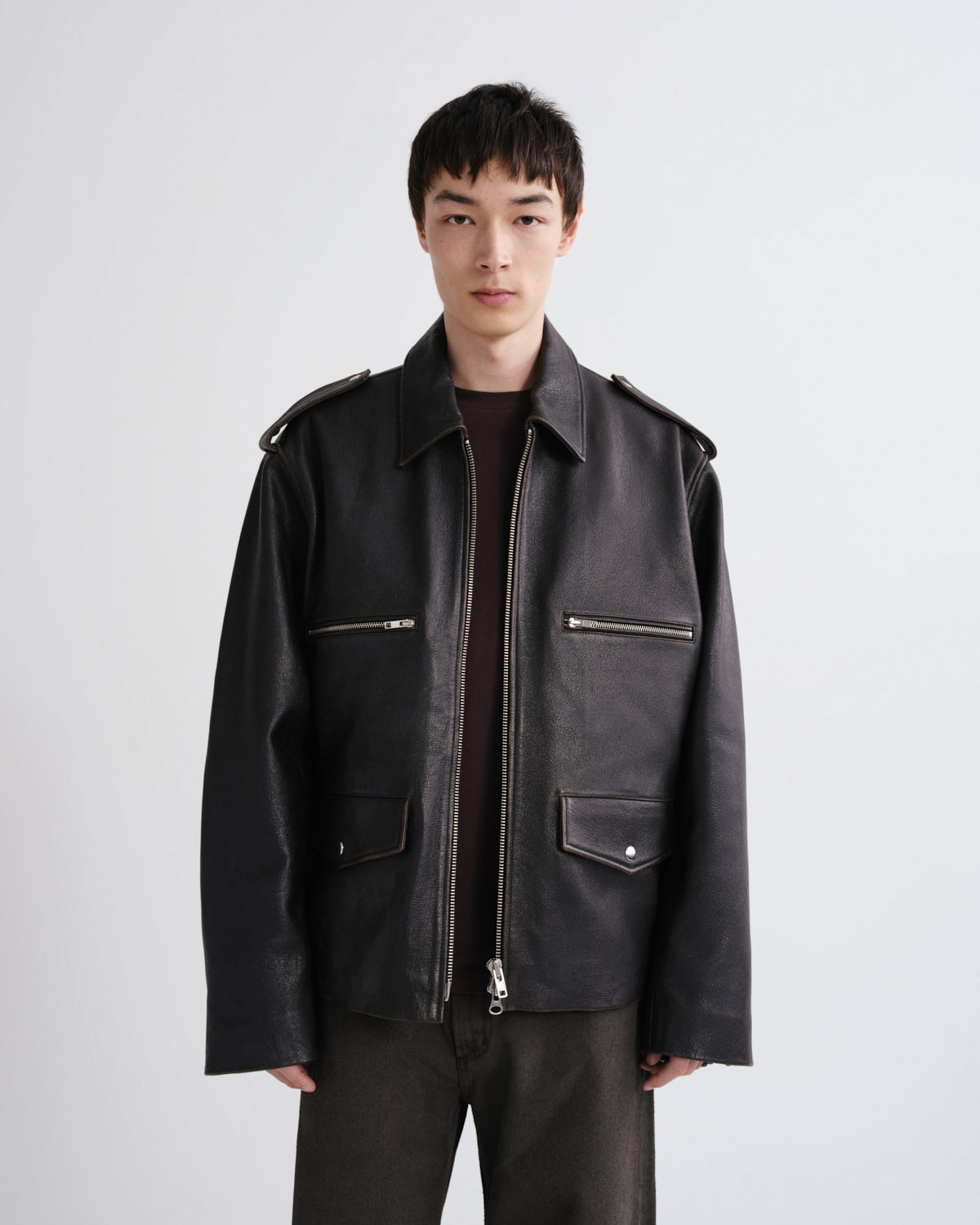 Man wearing a black leather jacket on a grey background