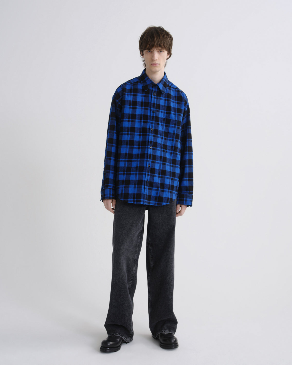 Person wearing a blue and black plaid shirt on a white background