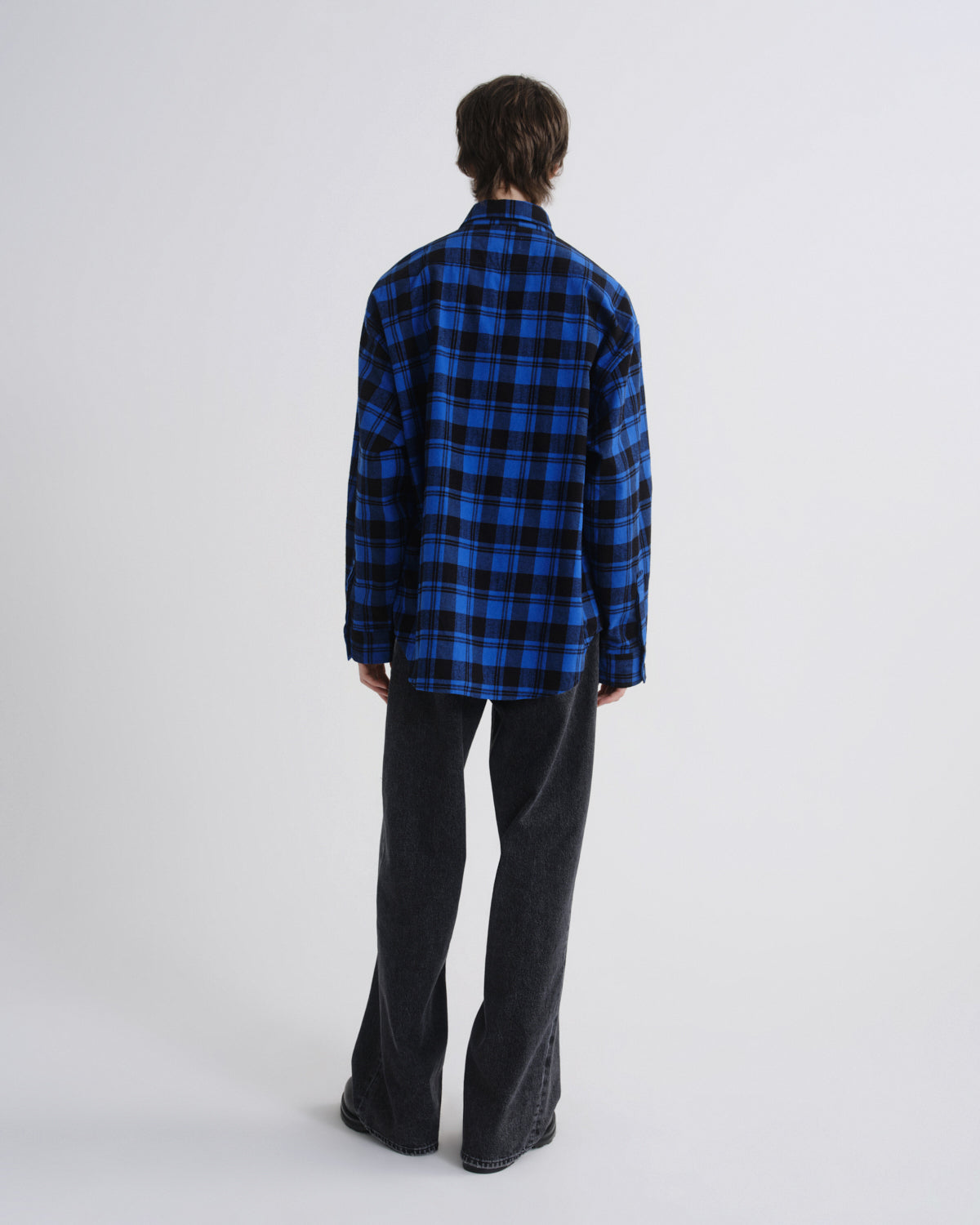 Person wearing a blue and black plaid shirt on a white background