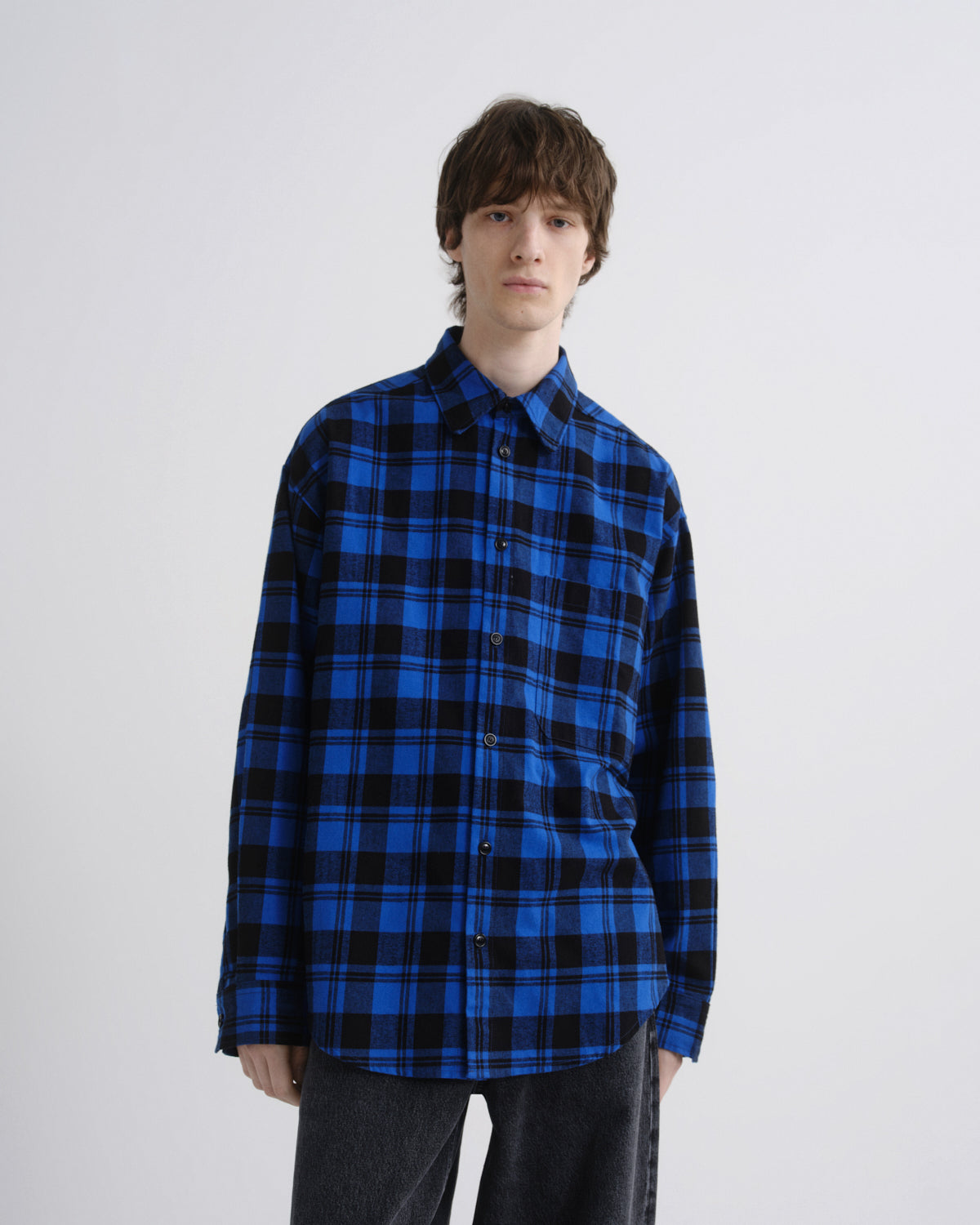 Person wearing a blue and black plaid shirt on a white background