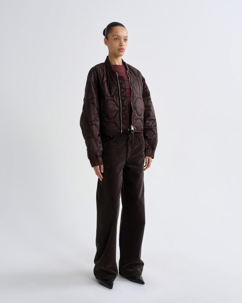 Person wearing a brown jacket and pants on a white background
