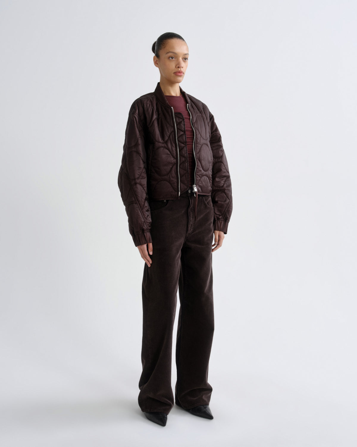 Person wearing a brown jacket and pants on a white background