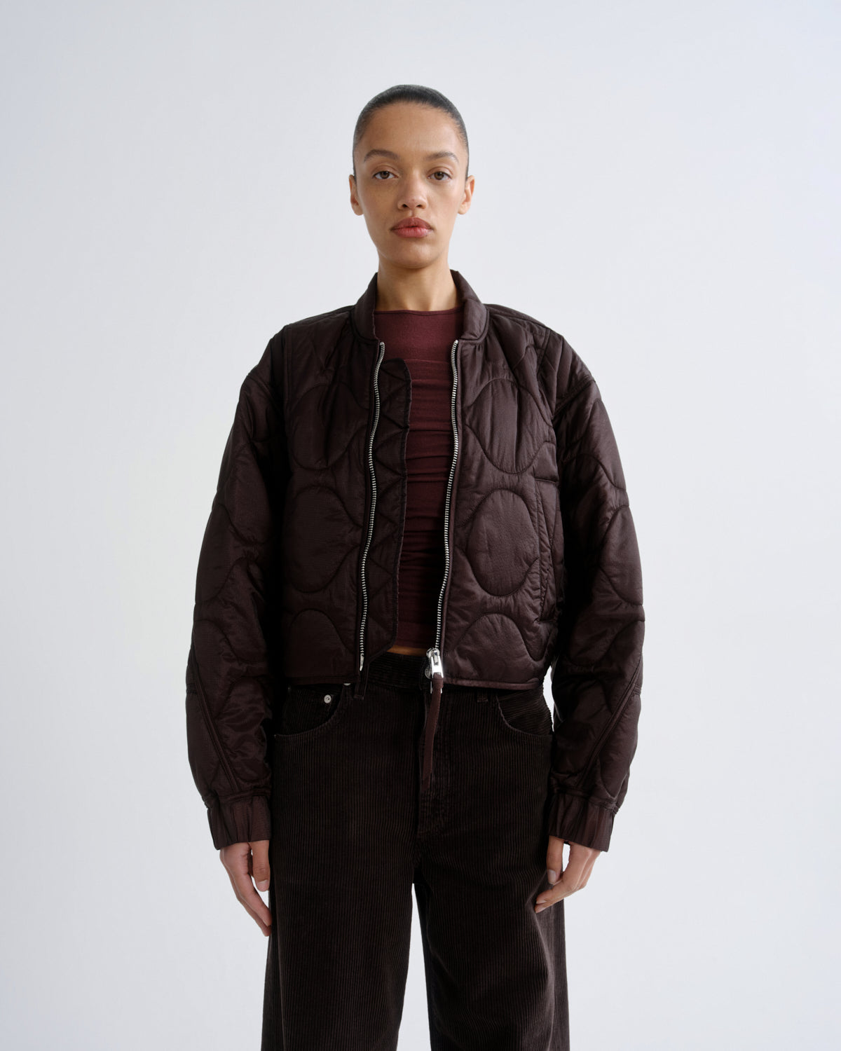 Person wearing a brown quilted jacket on a white background
