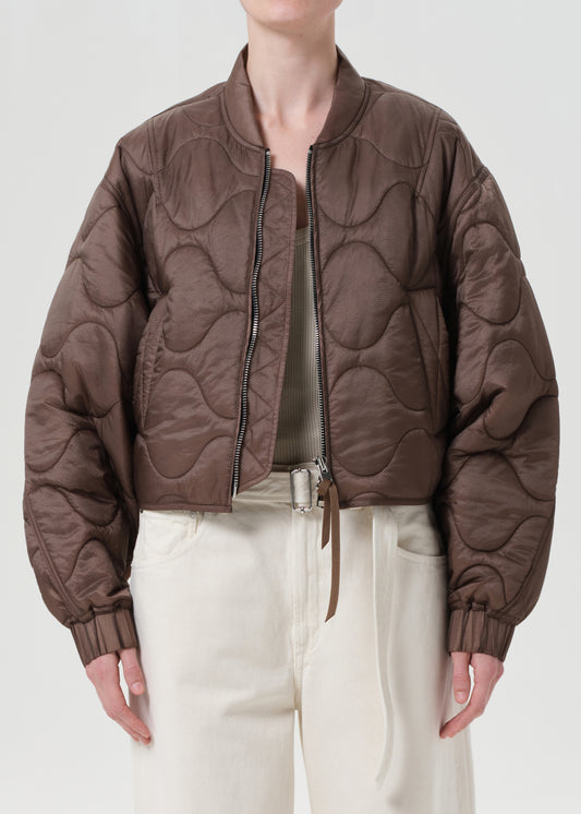 Person wearing a brown quilted jacket on a plain background
