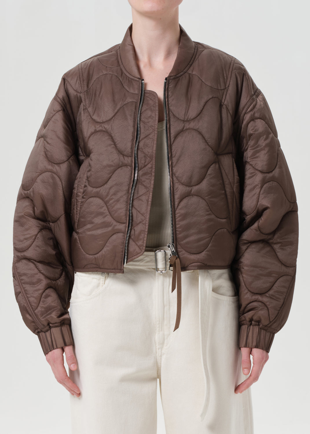 Person wearing a brown quilted jacket on a plain background