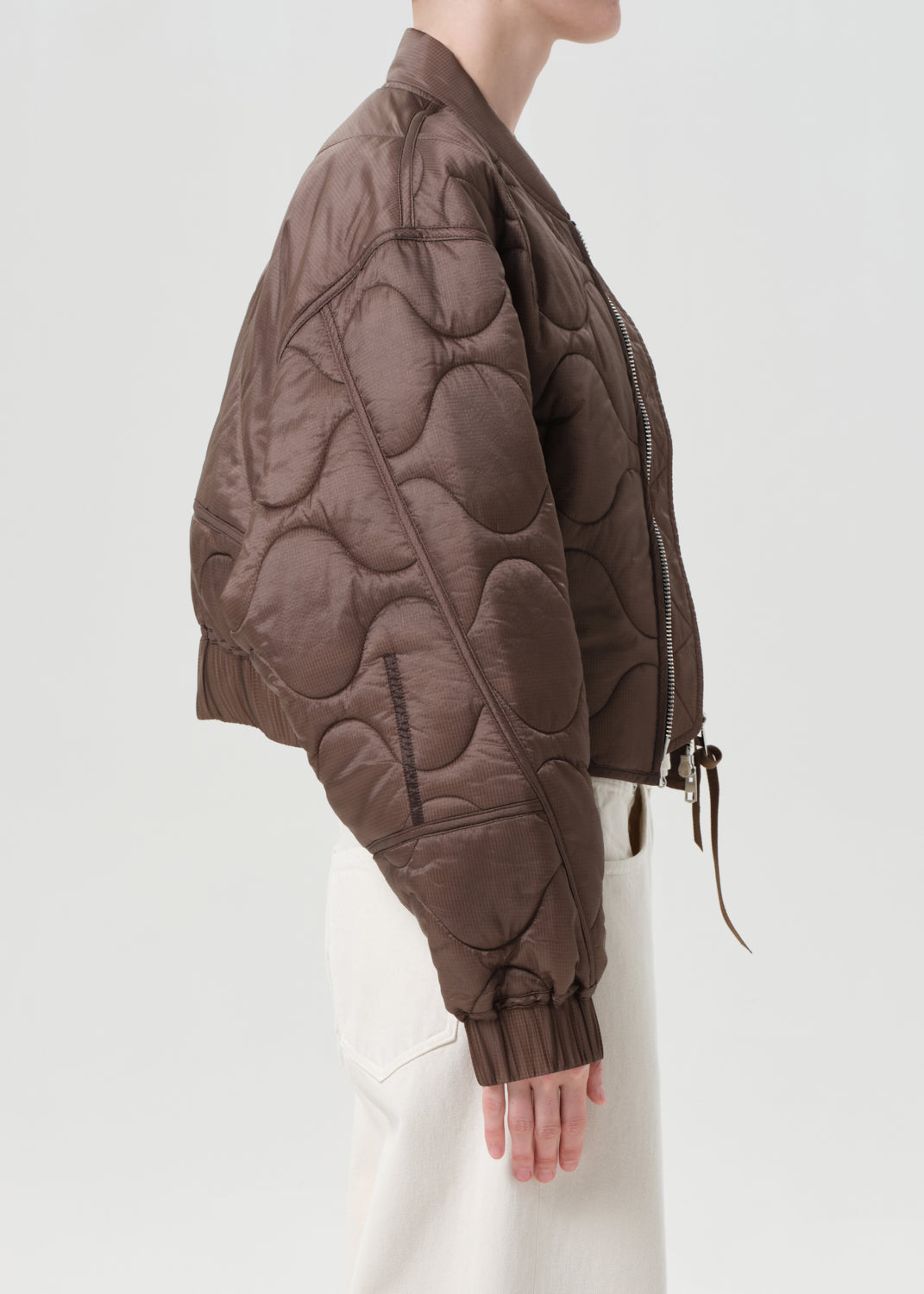 Brown quilted jacket worn by a person on a white background