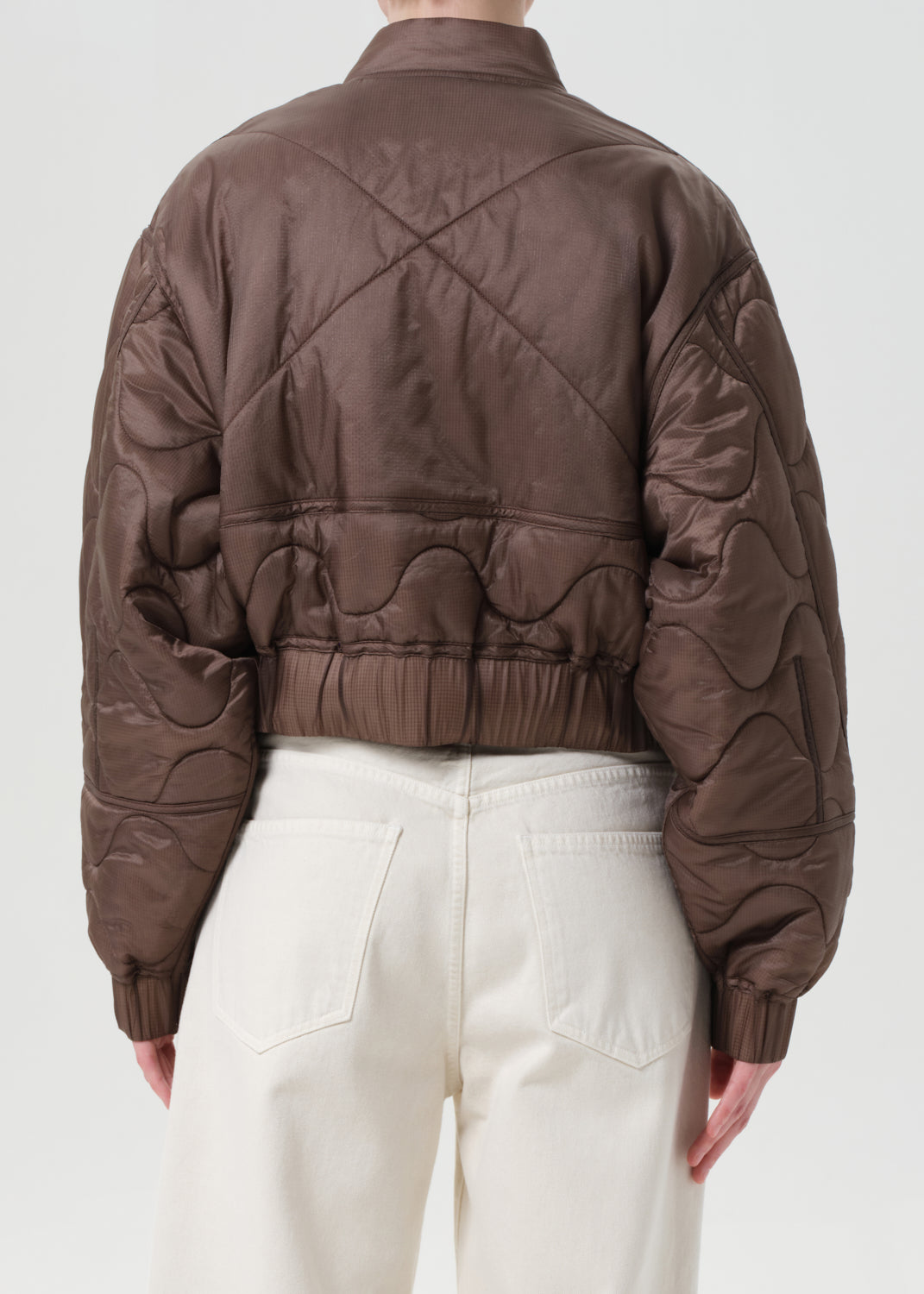 Brown quilted jacket worn by a person on a white background