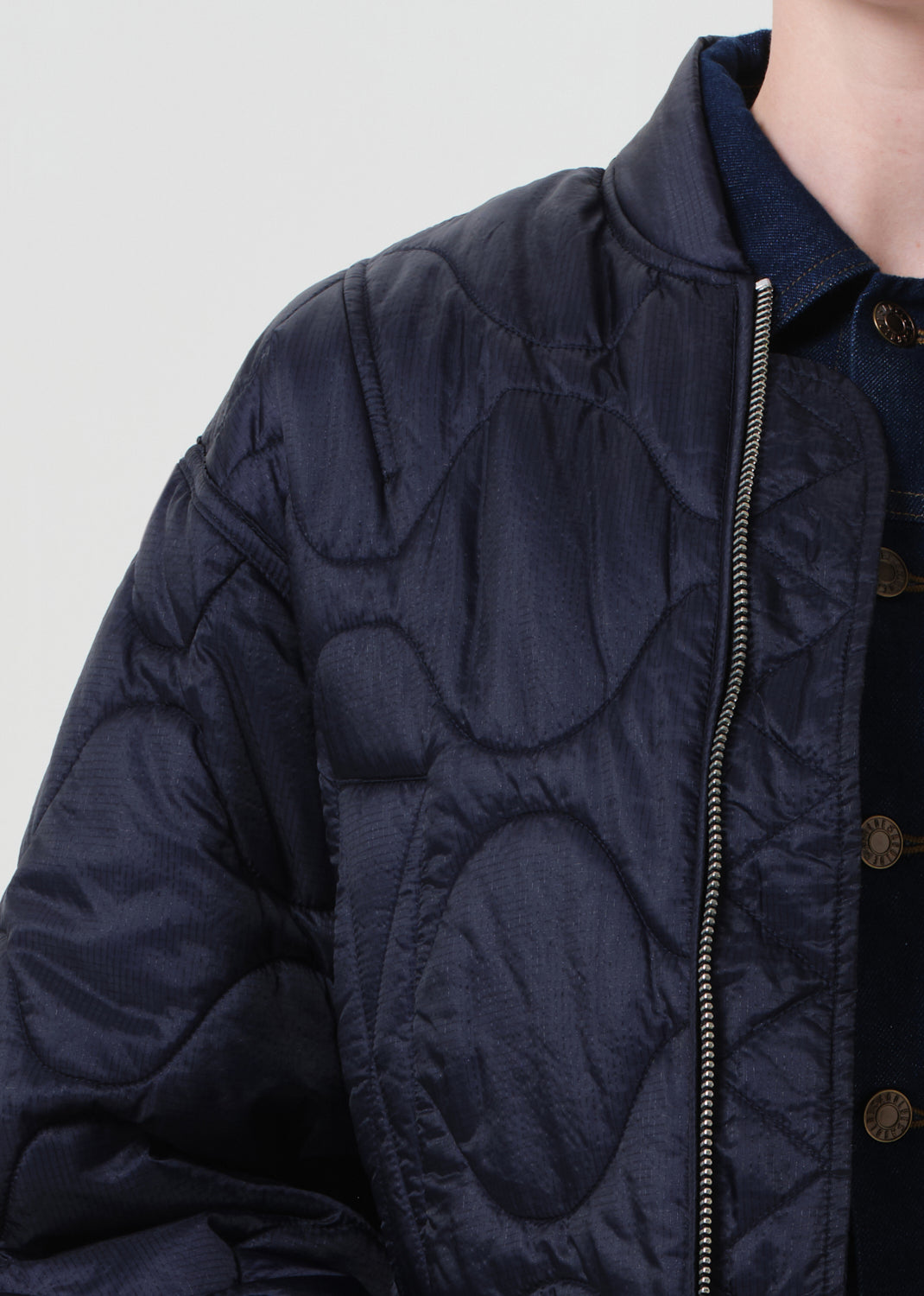 Navy quilted jacket with a zipper on a light gray background