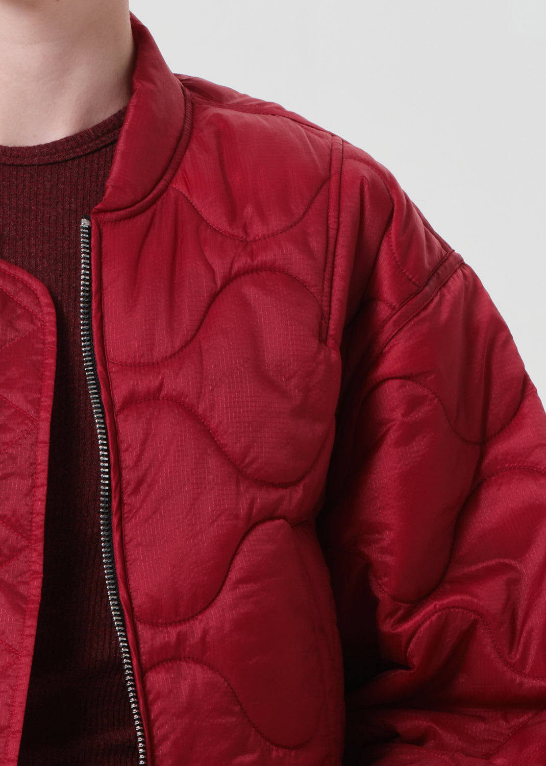 Red puffer jacket worn by a person on a plain background