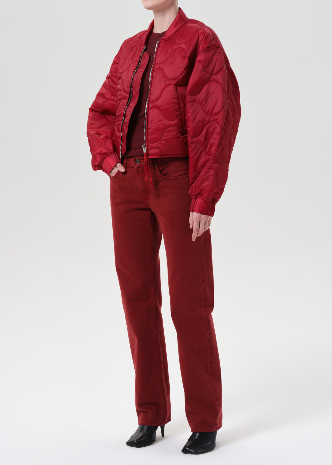 Person wearing a red quilted jacket and pants on a white background
