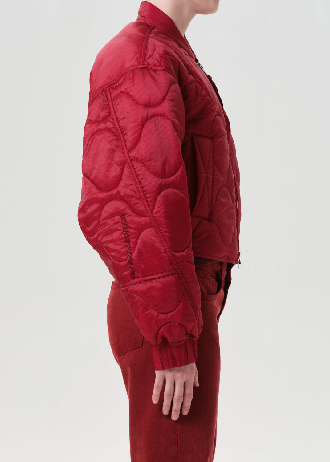 Red quilted jacket worn by a person on a light gray background