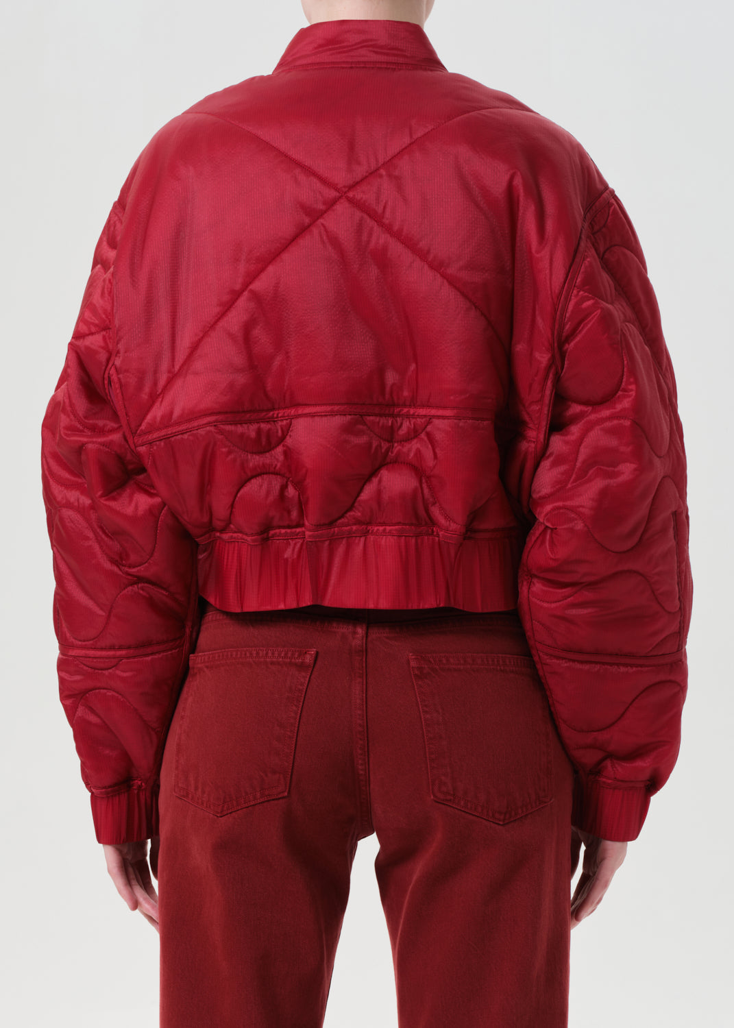 Red quilted jacket worn by a person on a white background