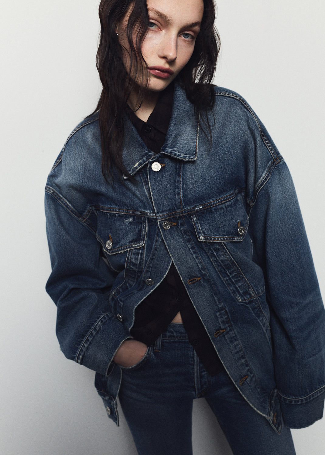 Person wearing a blue denim jacket against a plain background