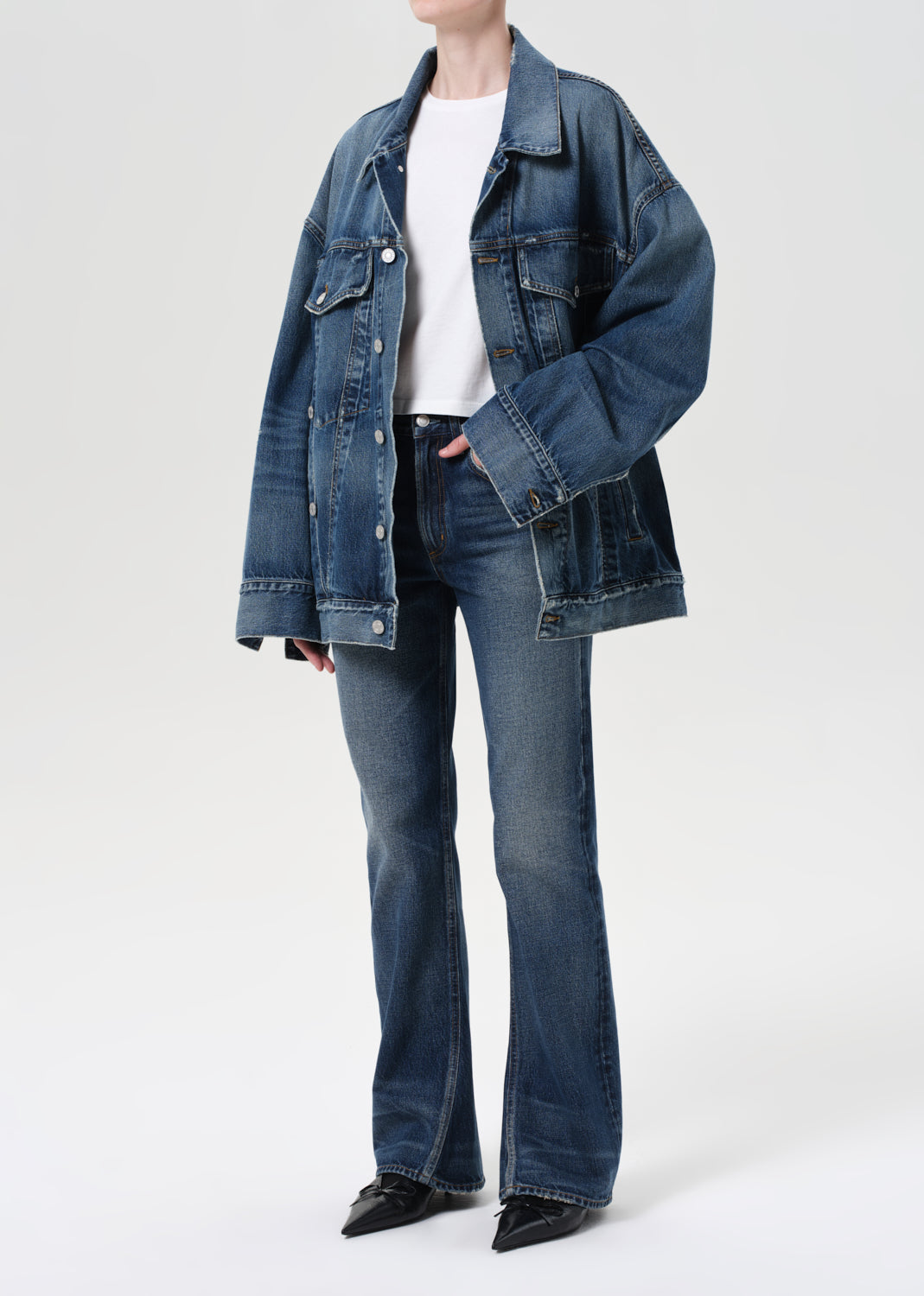 Person wearing a blue denim jacket and jeans on a white background