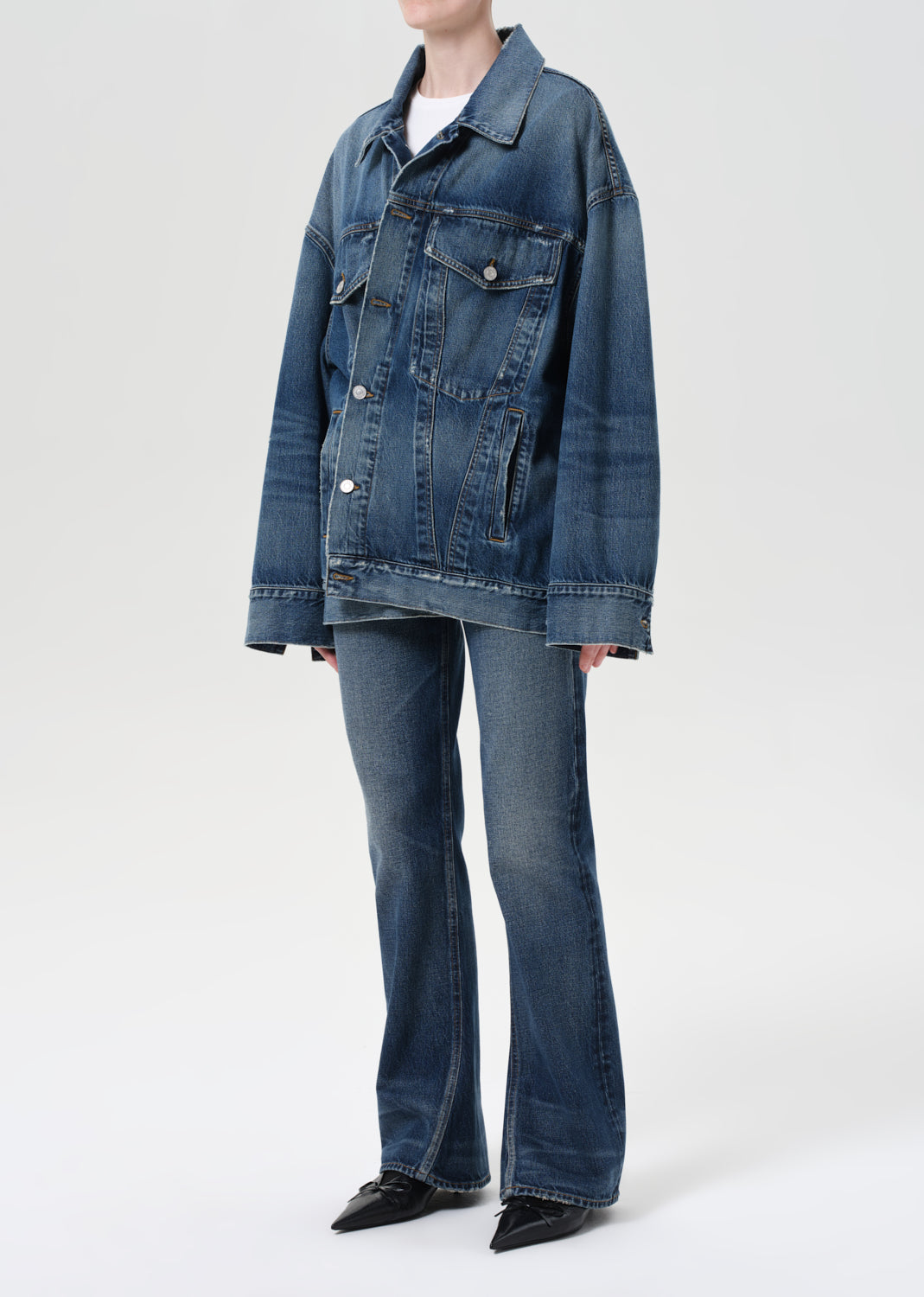 Person wearing a blue denim jacket and jeans on a white background
