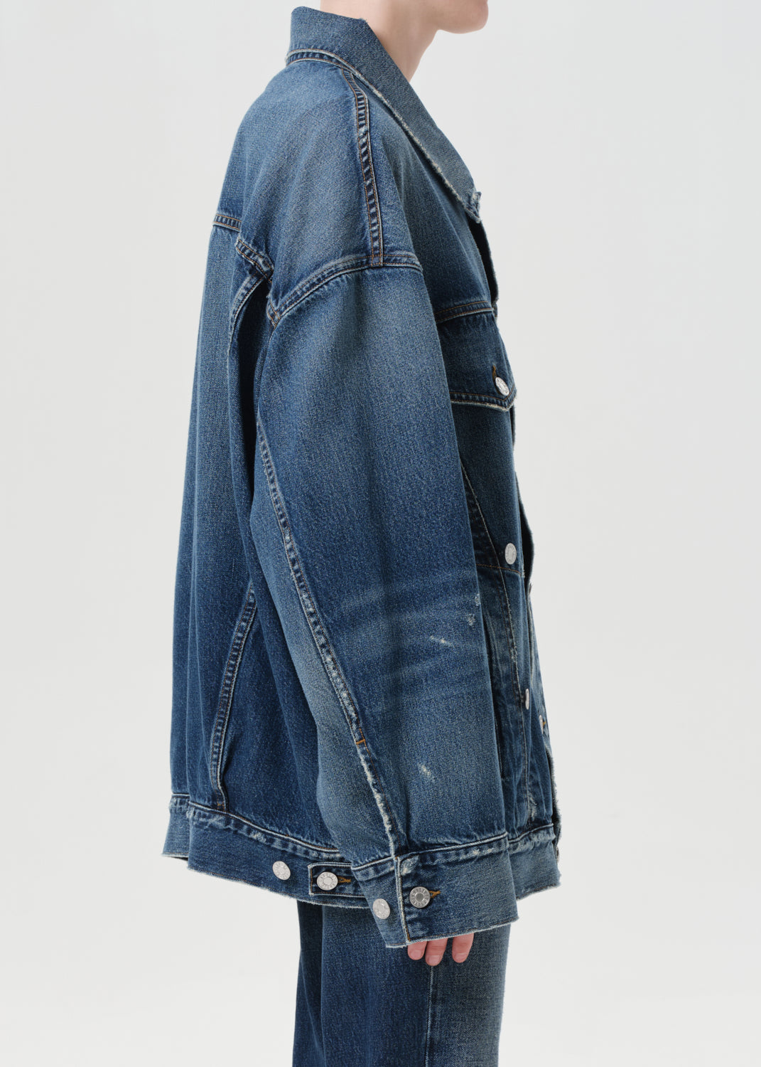 Blue denim jacket worn by a person on a light gray background