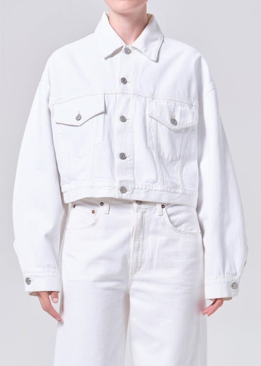 Person wearing a white denim jacket and pants on a plain background