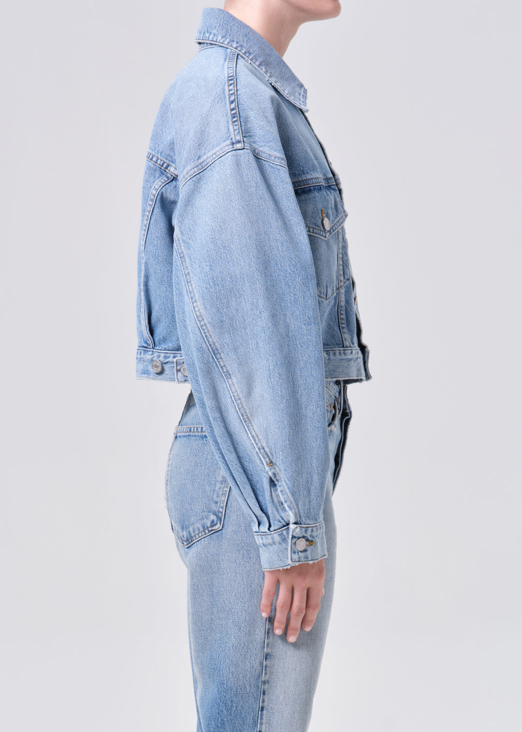 Light blue denim jacket worn by a person on a light gray background