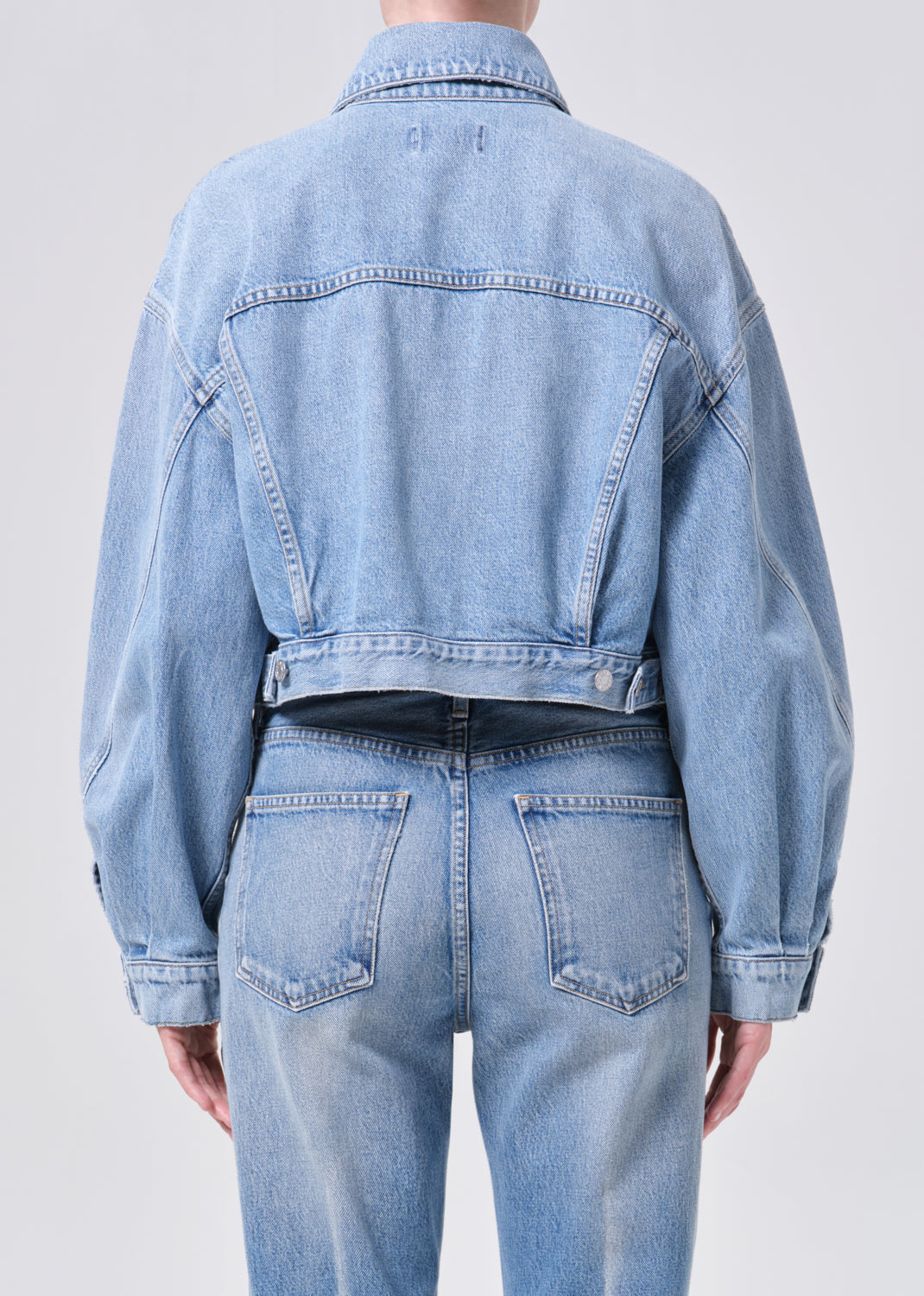 Light blue denim jacket and jeans on a plain background