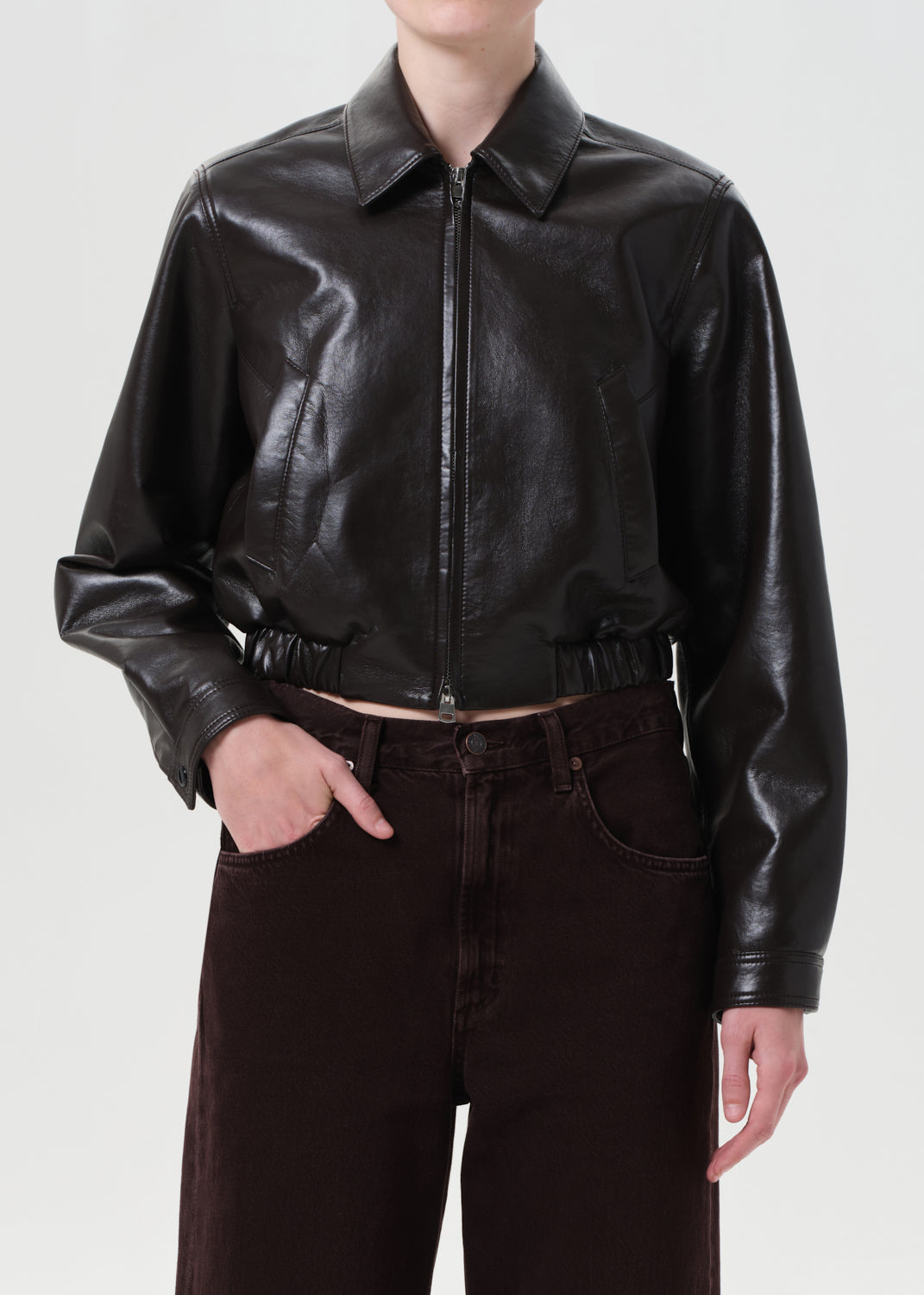 Person wearing a black leather jacket and dark jeans on a white background