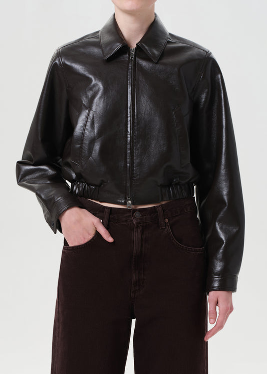 Person wearing a black leather jacket and dark jeans on a white background