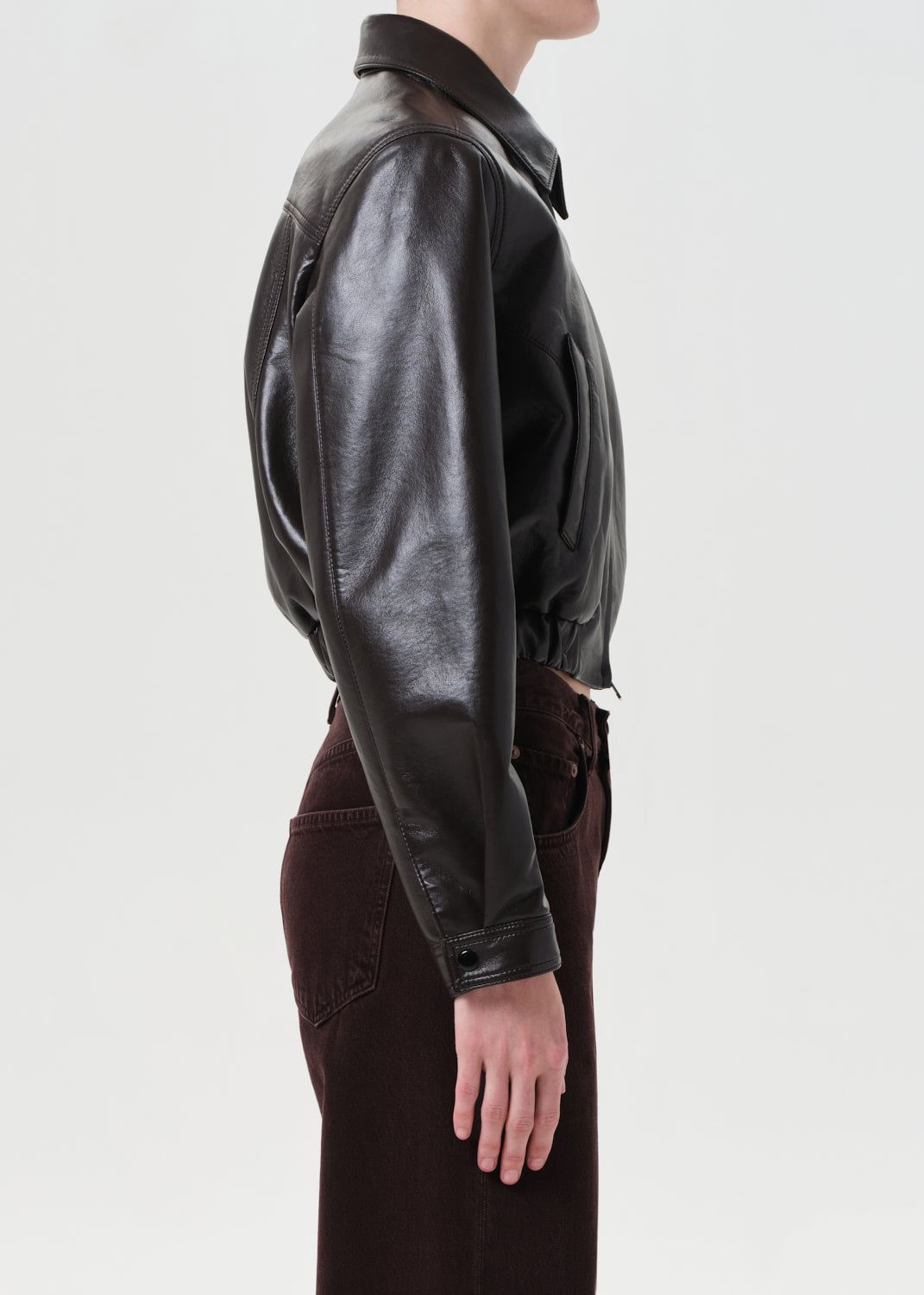 Person wearing a black leather jacket on a plain background