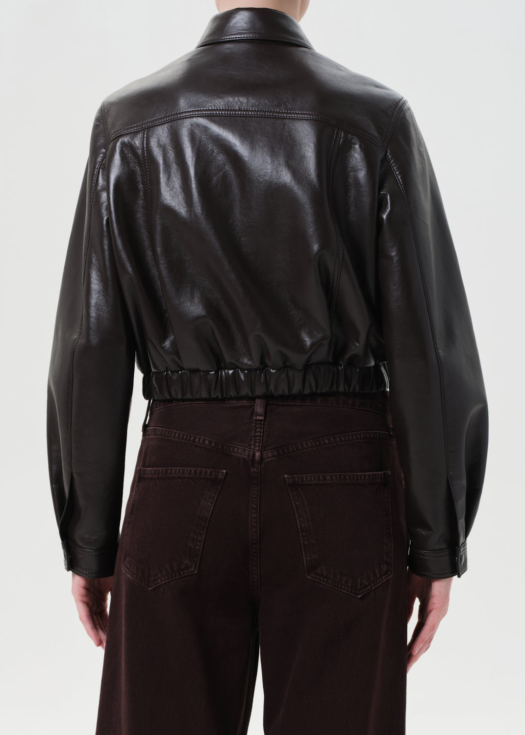 Person wearing a black leather jacket and dark pants on a white background