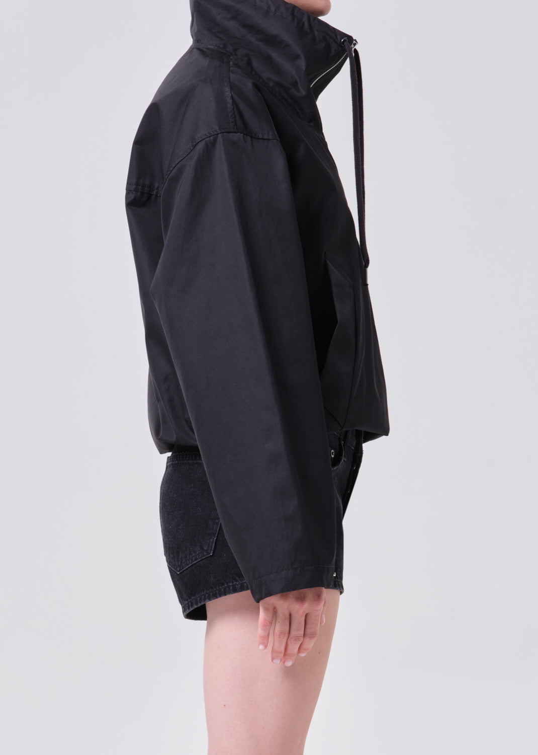 Person wearing a black raincoat on a light gray background