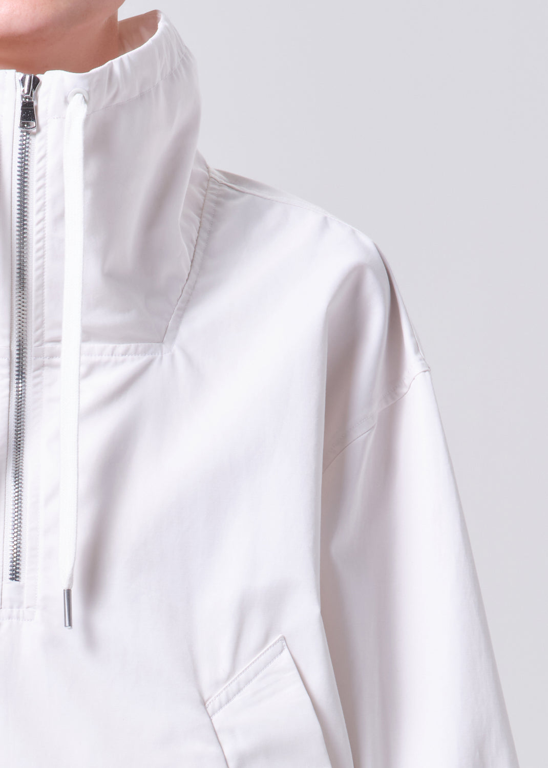 Close-up of a white jacket with a zipper on a light gray background