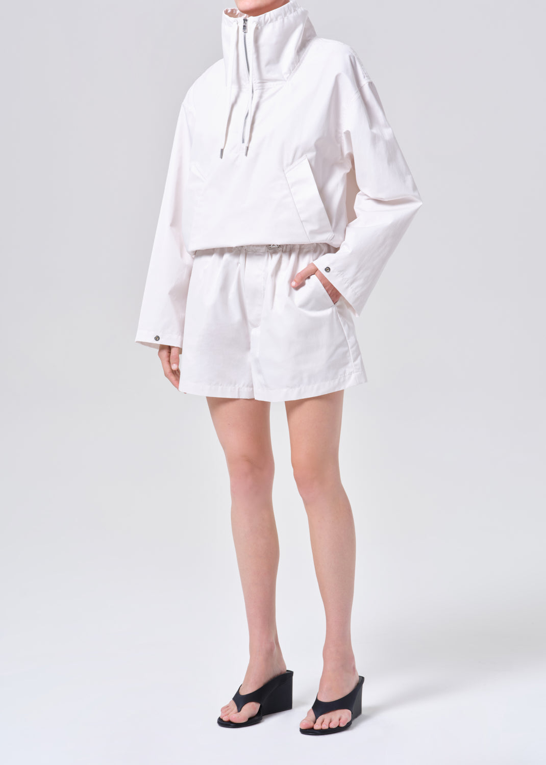 Person wearing a white outfit with shorts on a white background