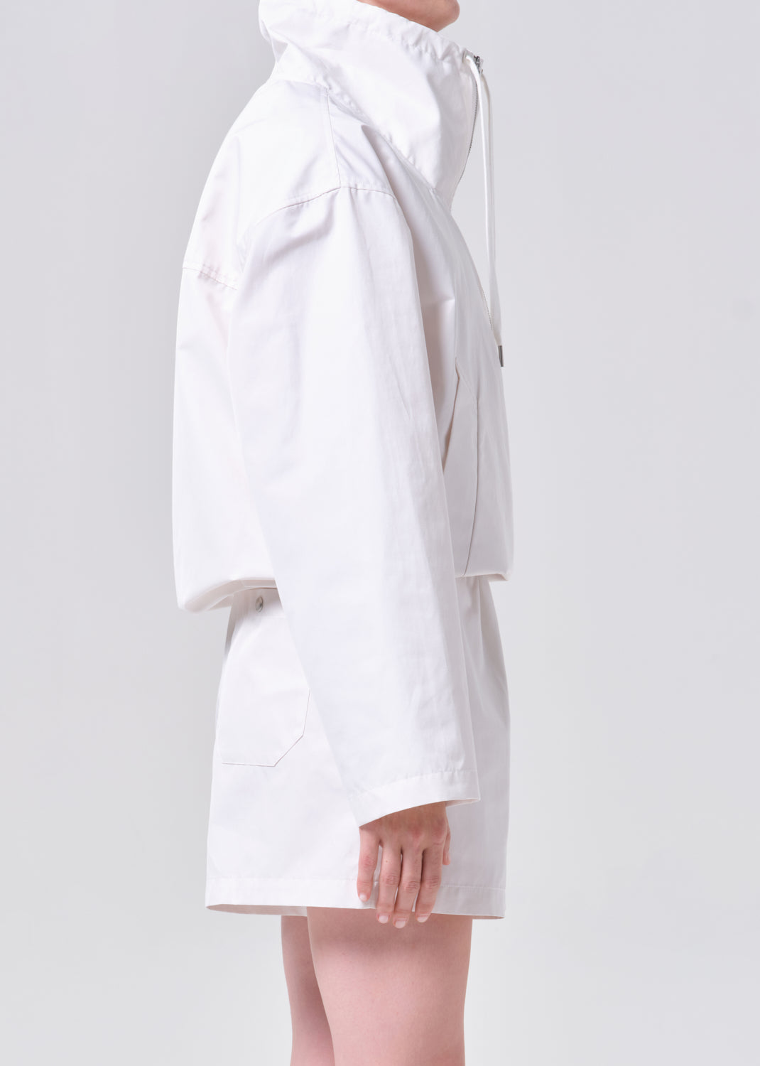 White raincoat worn by a person on a light gray background