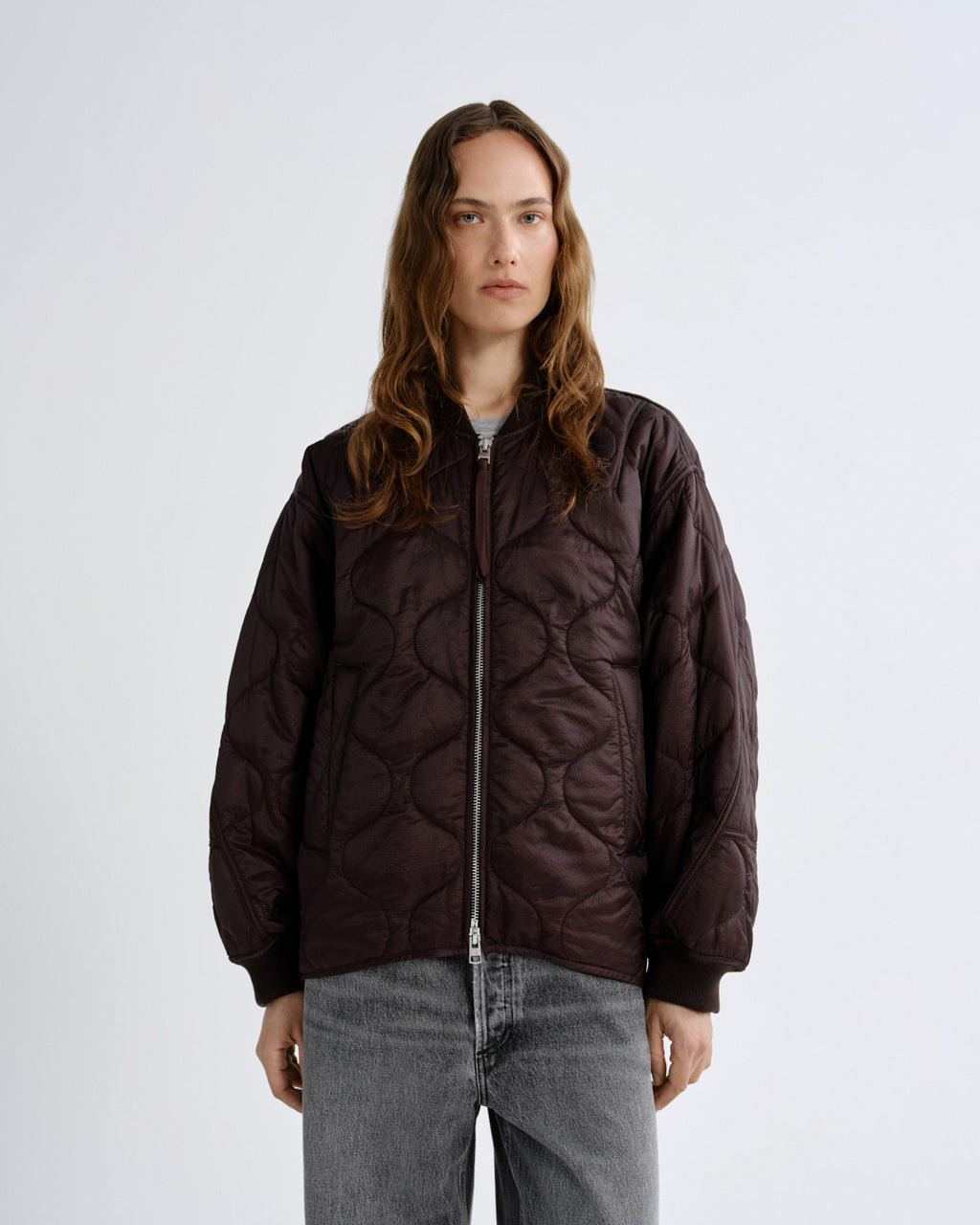 Person wearing a quilted brown jacket on a white background