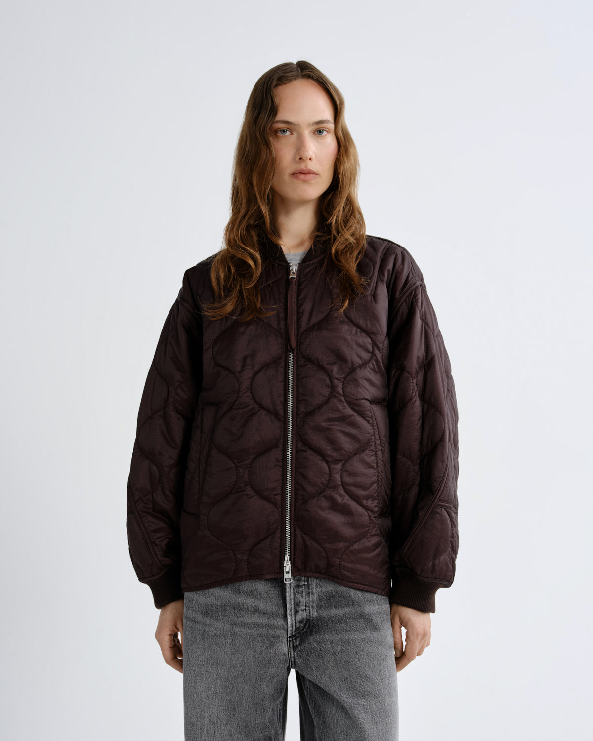 Person wearing a quilted brown jacket on a white background