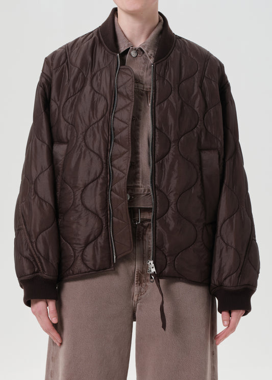 Person wearing a brown quilted jacket on a white background