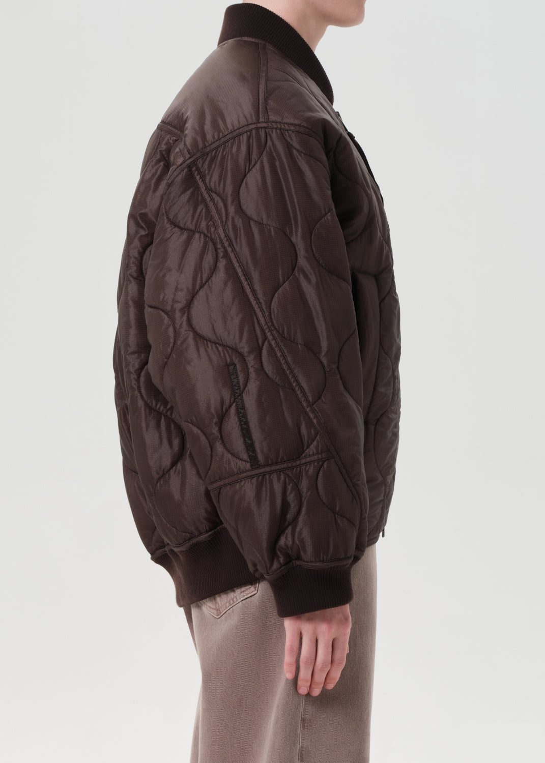 Brown quilted jacket worn by a person on a light gray background