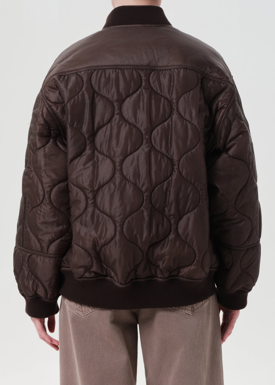 Brown quilted jacket worn by a person on a white background