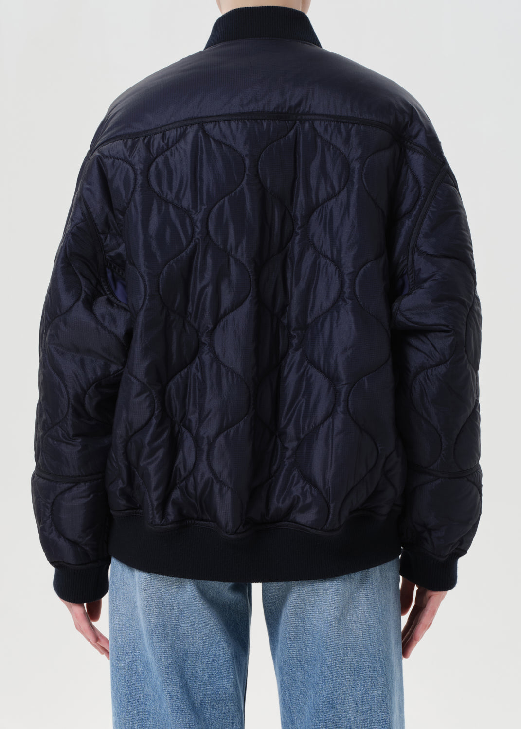 Black quilted jacket worn by a person on a white background