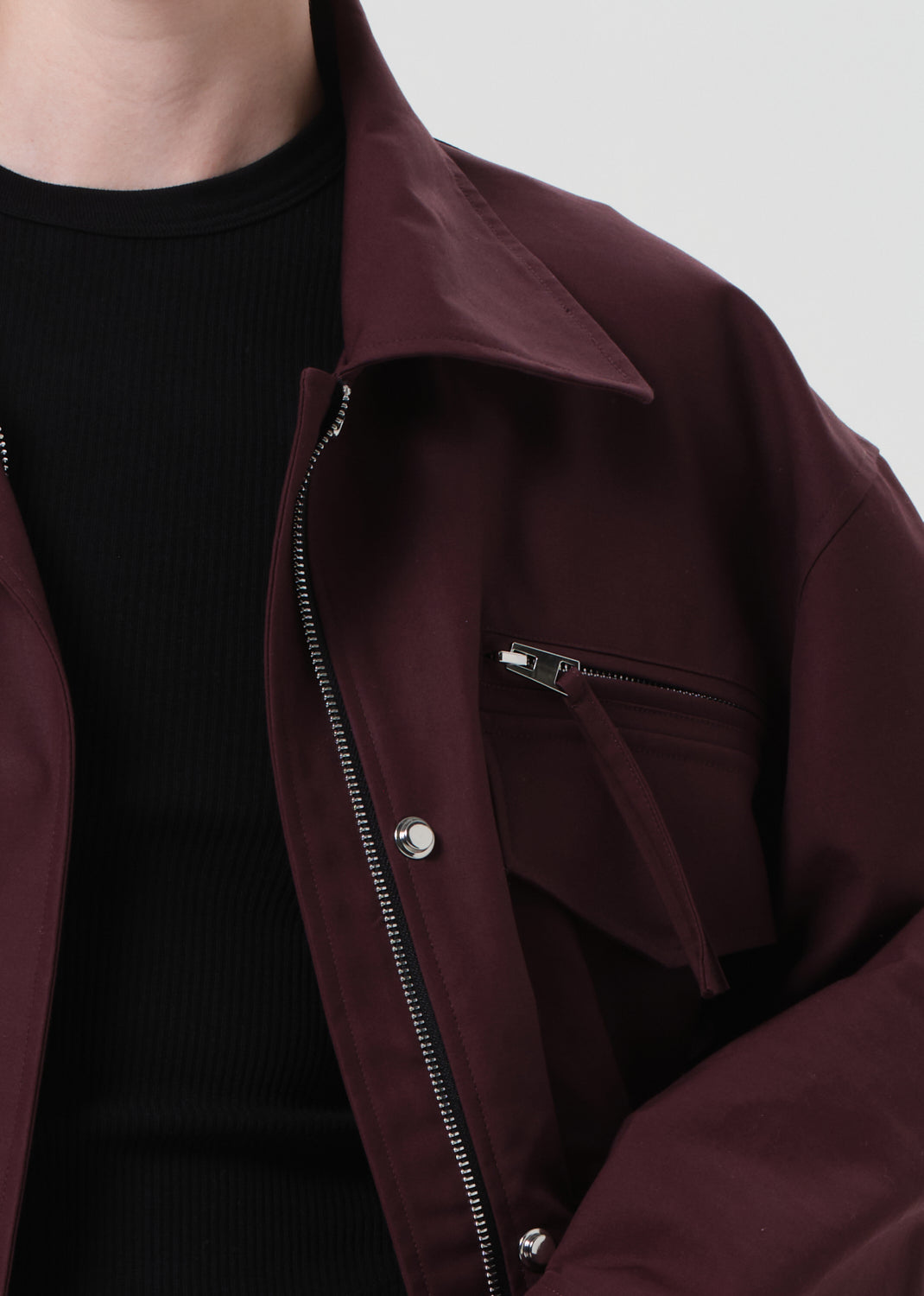 Close-up of a maroon jacket with a zipper on a plain background