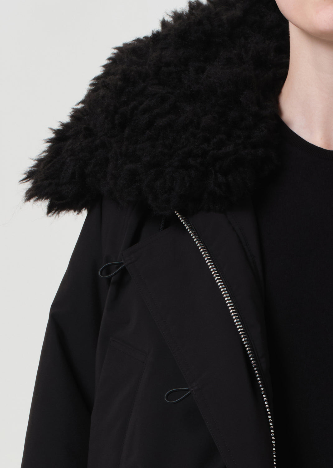 Black coat with fur hood on a plain background