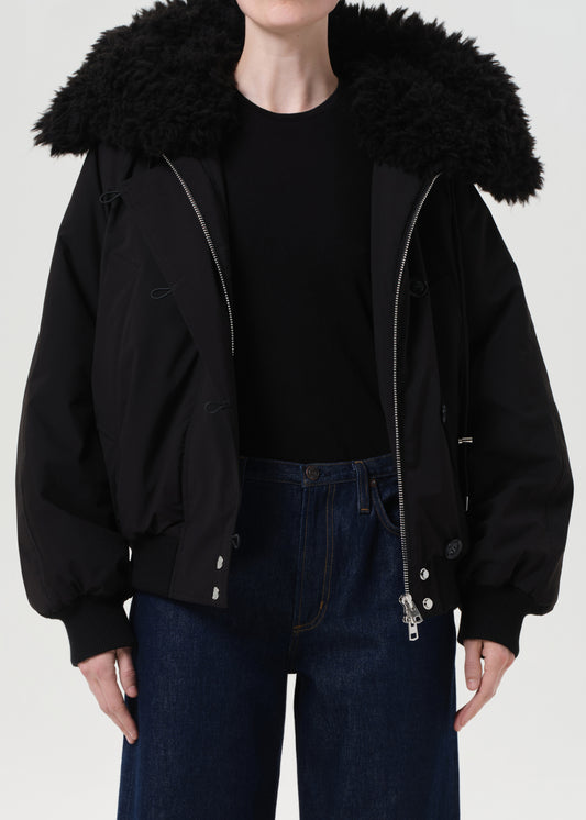 Person wearing a black jacket with a fur-lined hood on a white background